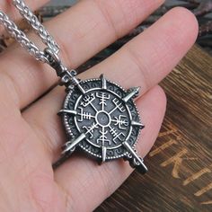 a person holding a compass necklace in their hand