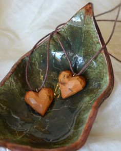 two heart shaped wooden ornaments in a green bowl