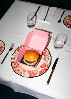 a pink box sitting on top of a plate next to silverware and utensils