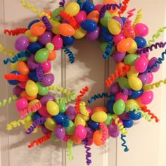 a wreath made out of balloons and streamers on the front door to celebrate someone's birthday