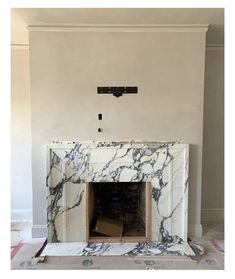 the fireplace is being installed in the living room with white walls and black marble surround