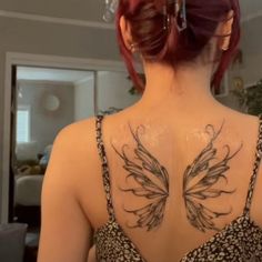 a woman with red hair and tattoos on her back is standing in front of a mirror