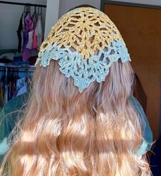 the back of a woman's head wearing a crocheted yellow and blue hat