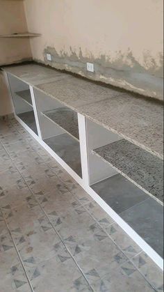 an empty room with some shelves on the wall and tile flooring in front of it