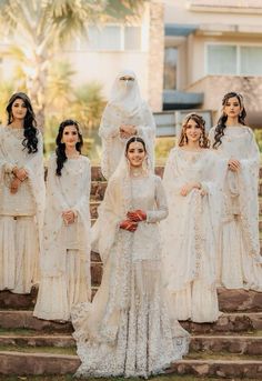 a group of women in white dresses standing on steps with one woman wearing a veil