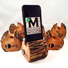 a cell phone that is sitting on some wood logs and has the words manmade woods written on it