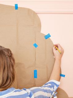 a woman writing on a piece of cardboard with blue adhesive tape around her head