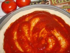 a pizza sitting on top of a pan covered in sauce next to tomatoes and a book