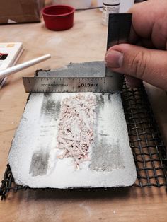 a person is using a ruler to measure something on a piece of paper that has been placed on a table