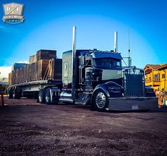 a large semi truck parked in front of a yellow building