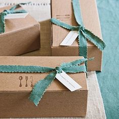 three boxes wrapped in brown paper with green ribbon and tags tied around the top one