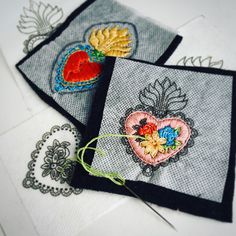 three embroidered cards with hearts and flowers on them