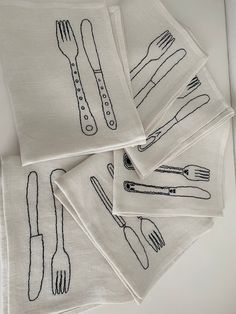 four embroidered napkins with utensils on them sitting on top of a table