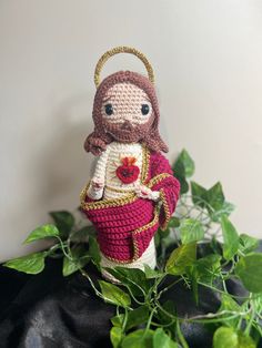 a crocheted doll is sitting on top of a plant