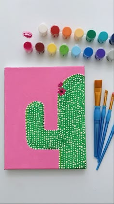 an art project with paint and markers on the table next to it is a cactus