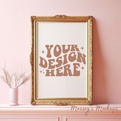 a gold frame with the words your design here on it in front of a pink wall