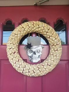 a wreath made out of wine corks with a skull wearing a hat on it