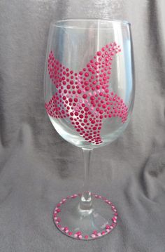 a wine glass decorated with pink dots and a starfish on the bottom is sitting on a gray surface