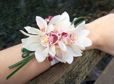 a person's hand with a wrist corsage made out of white and pink flowers