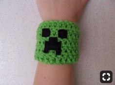 a green wristband with black squares on it and a small square in the middle