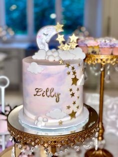 a white and gold cake with stars on it sitting on a table next to a window