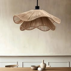 a wooden table topped with a white vase next to a light hanging from the ceiling