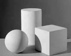 three white objects sitting next to each other on top of a gray surface with shadows