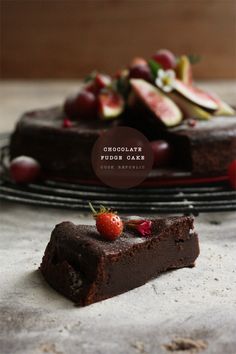 a piece of chocolate cake sitting on top of a table next to a plate with fruit