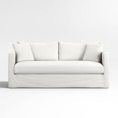 a white couch with four pillows on it's back and one arm facing the camera