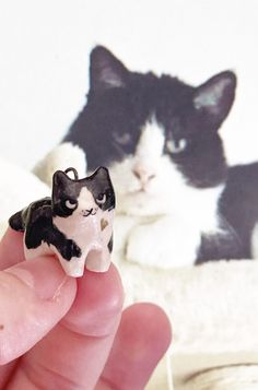 a small black and white cat figurine sitting on top of someone's finger