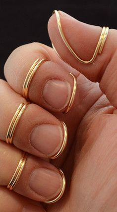 a woman's hand with three gold rings on her fingers and one ring in the middle