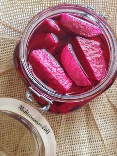 a jar filled with red pickles sitting on top of a table