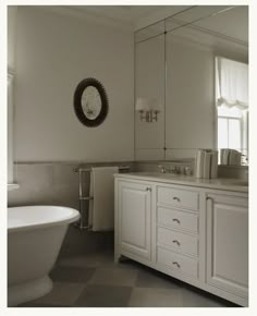 a white bath tub sitting next to a bathroom sink under a mirror on top of a wall