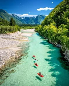 three kayakers are floating down the river with mountains in the background