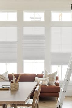 a living room filled with furniture and windows covered in white cellular shade shades on the windows