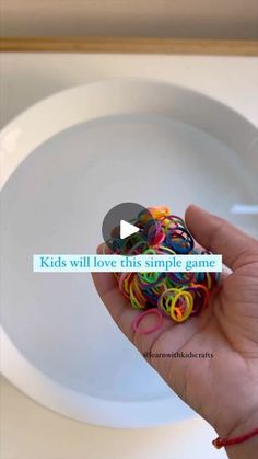 a hand holding a bunch of colorful bracelets in front of a white plate with the words kids will love this simple game