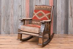 an old rocking chair on a wooden floor in front of a wall with wood planks