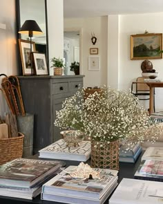 a table topped with lots of books and vases filled with flowers on top of it