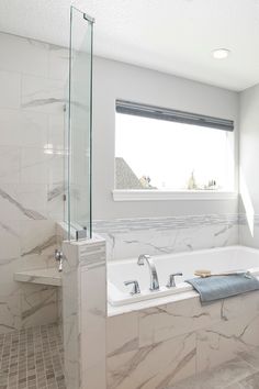 a bathroom with a large tub and walk in shower next to a window on the wall