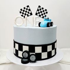 a birthday cake decorated with a race car and the number one on it's top