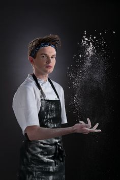 a man in an apron is holding out his hands with powder coming out of it