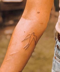 a person's arm with a tattoo on the left side of their arm and an outline of a bird