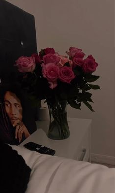 a vase filled with pink roses sitting on top of a table next to a cell phone