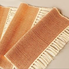 three orange and white towels folded on top of each other with fringes around them