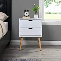 a white nightstand with two drawers and a clock on the side table next to it