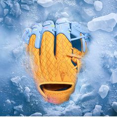 a yellow and blue baseball glove laying on top of ice with water behind the glove