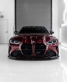 the front end of a red sports car in a garage with an open door behind it