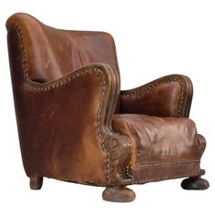 a brown leather chair with nail polishing on the armrests and foot rest