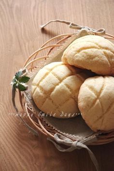 three round pastries sitting in a wicker basket on top of a wooden table