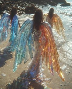 three women with wings are walking in the water